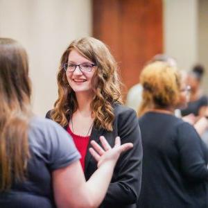 An attendee of a networking fair smiles at a presenter.